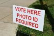 Sign showing where to vote on election day at the polling place. Vote Here, Photo ID Required