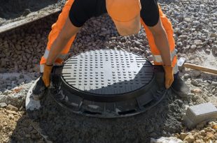 Installing cast iron sewer hatch on a concrete base of installation of water main sewer well in the