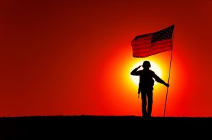 USA Soldier with flag saluting on sunset horizon