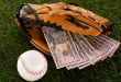 dollar banknotes in baseball glove near ball on green grass, sports betting concept
