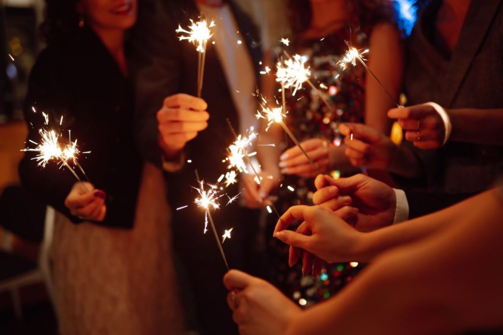 Sparkling sparklers in hands. Playing firework to celebrate winter holidays with friends at party