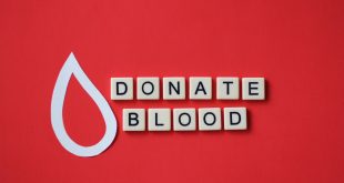 Overhead of tiles with “Donate blood” phrase spelled on red background.