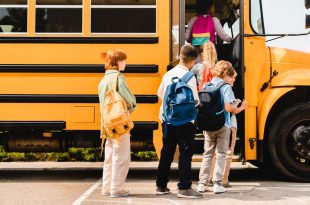 Schoolchildren kids pupils group of mixed-race classmates boarding school bus before lessons