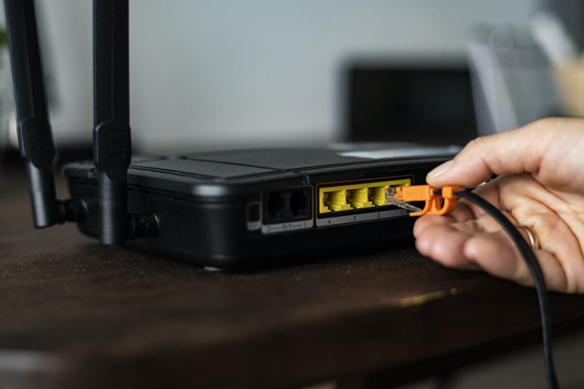 man plugging in an ethernet cable to a wireless router