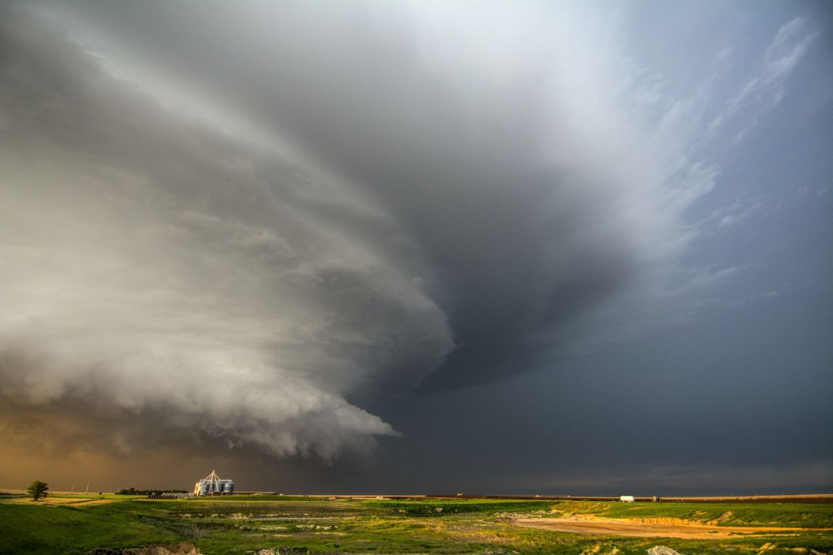 a tornado producing supercell thunderstorm spinning over ranch land at sunset near leoti, kansas