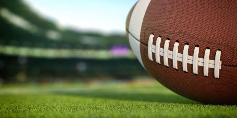 american football ball on grass of football arena