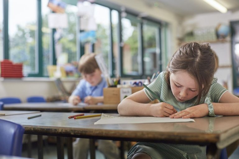 schoolgirl writing in classroom lesson in primary school