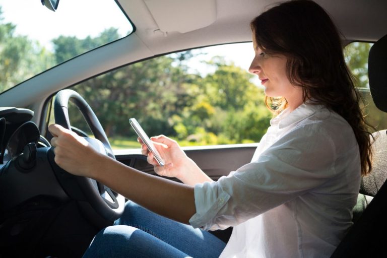 woman using mobile phone while driving a car