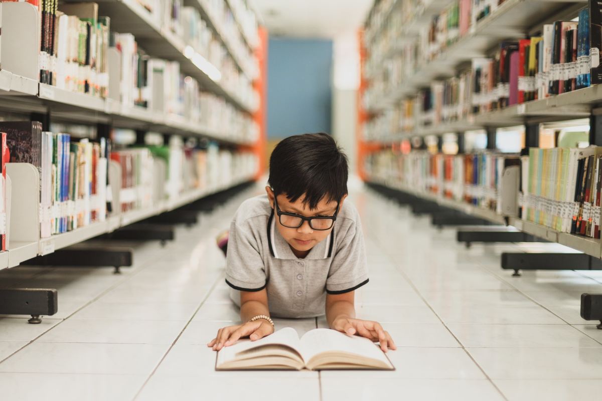 smart school boy reading a book at the library