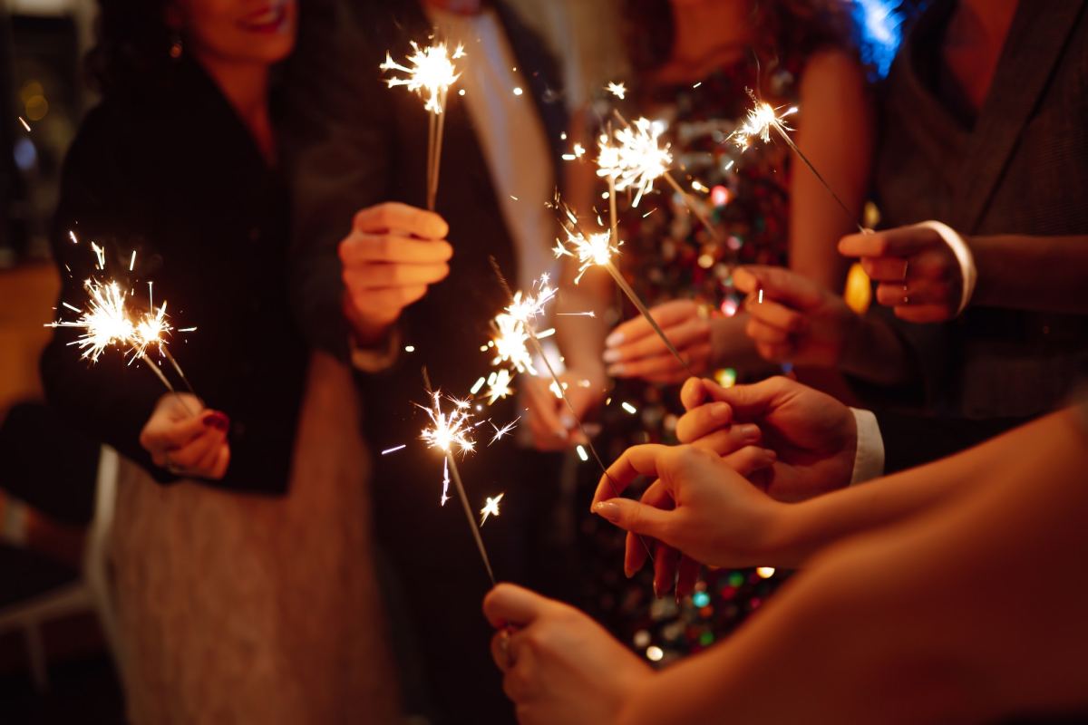 sparkling sparklers in hands. playing firework to celebrate winter holidays with friends at party