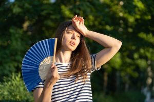 young woman suffer heatstroke outdoors. unhappy girl feel bad of hot temperature touch forehead