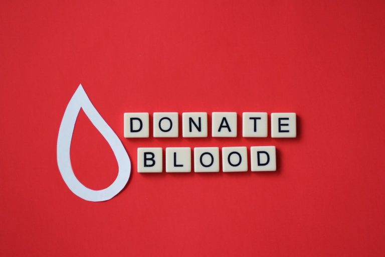 overhead of tiles with “donate blood” phrase spelled on red background.