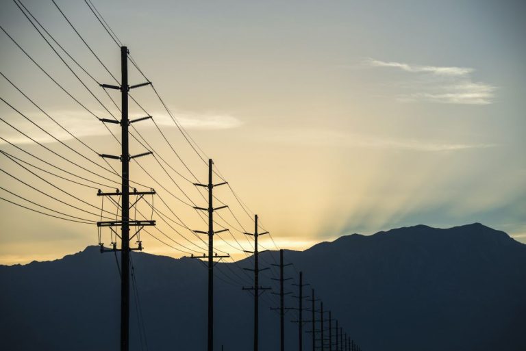 a row of poles and communication or power lines at sunset.