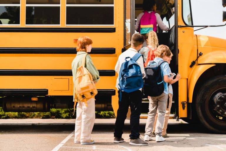 schoolchildren kids pupils group of mixed race classmates boarding school bus before lessons