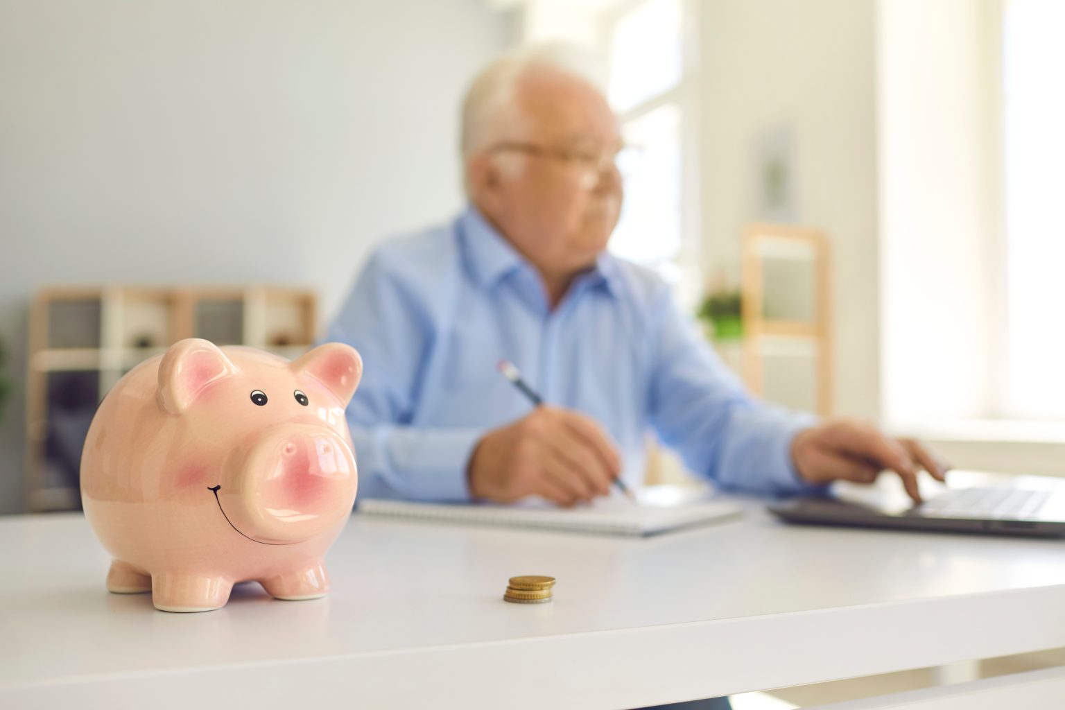 piggy,bank,in,soft,focus,on,desk,with,blurred,elderly