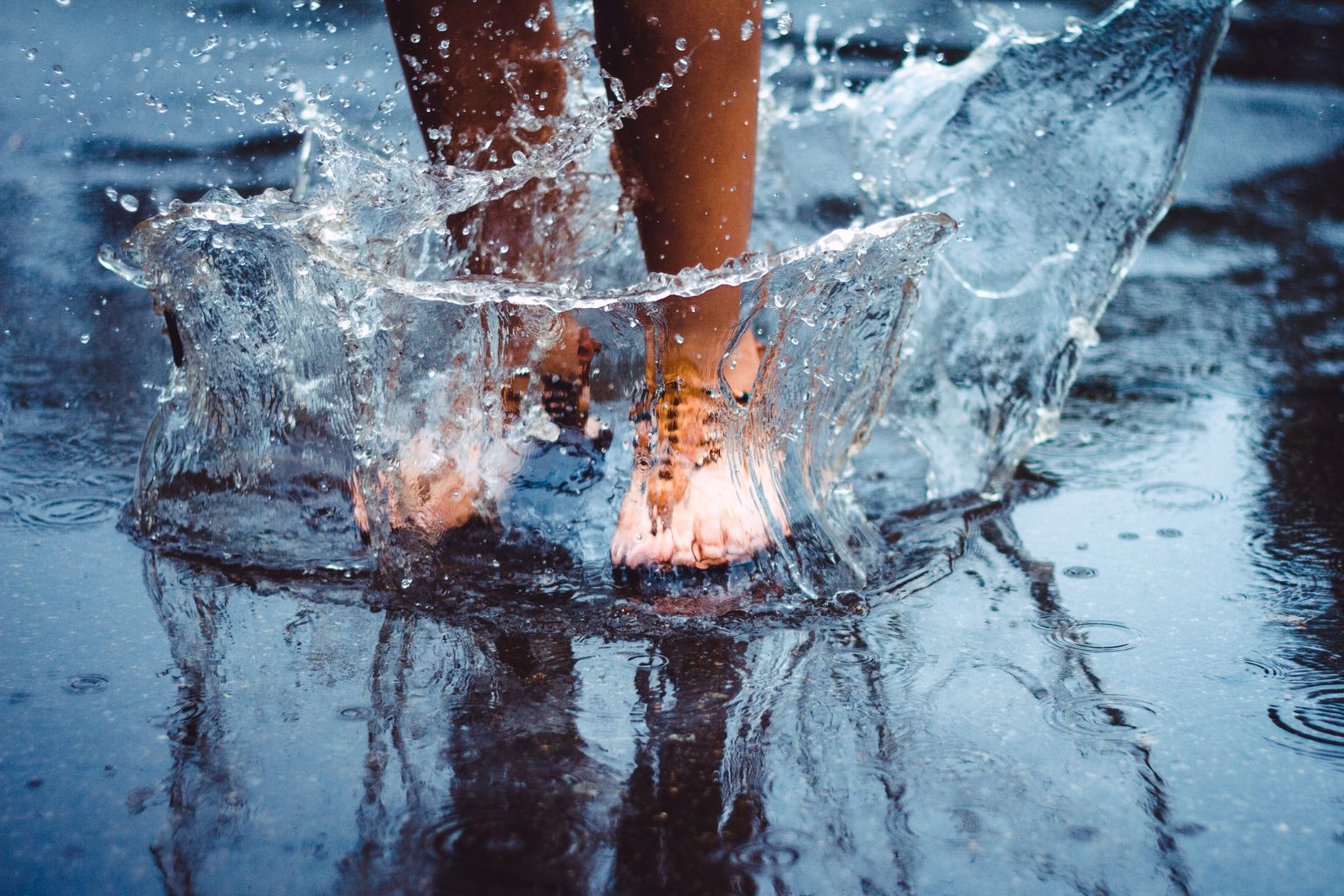 unrecognizable,person,(female),is,splashing,water,in,a,puddle,on